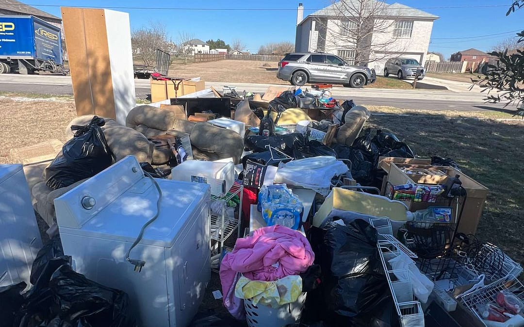 loads of junk sit in the yard as there is a writ of possession in progress in Kyle, TX with the constable and IREP Junk Removal present
