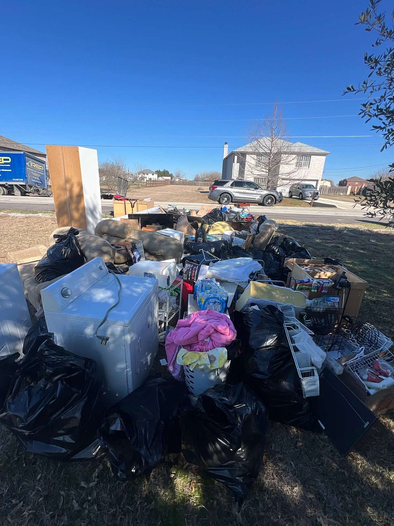 loads of junk sit in the yard as there is a writ of possession in progress in Kyle, TX with the constable and IREP Junk Removal present